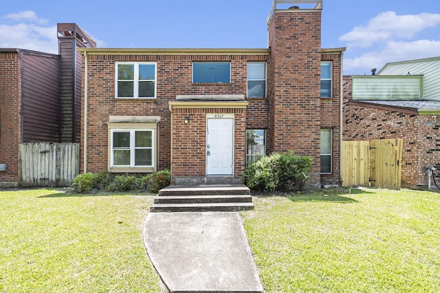 multi unit property featuring brick siding, a front yard, and fence