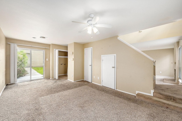 interior space with carpet flooring, a ceiling fan, visible vents, stairs, and baseboards