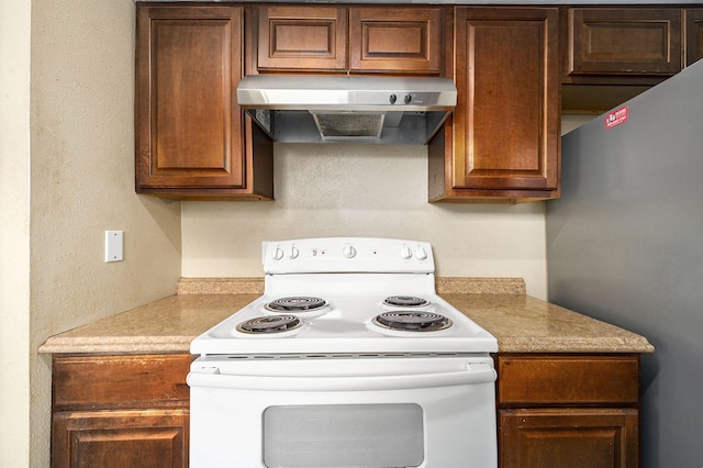 kitchen featuring electric stove, light countertops, freestanding refrigerator, and under cabinet range hood