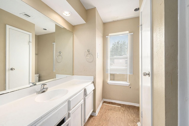 bathroom featuring toilet, wood finished floors, vanity, visible vents, and baseboards