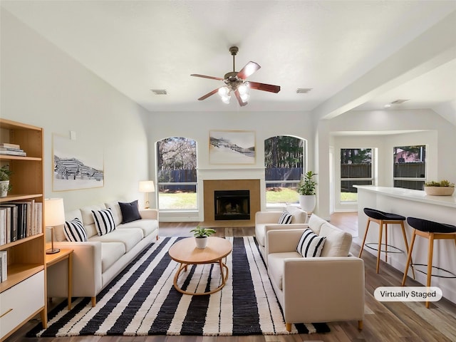 living area with a fireplace with flush hearth, a wealth of natural light, wood finished floors, and visible vents