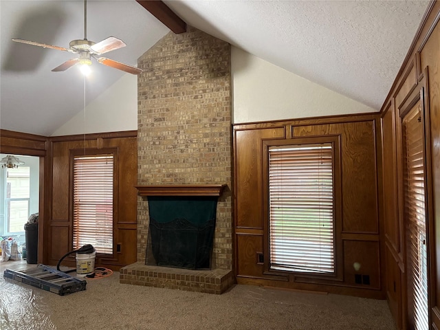 unfurnished living room with carpet flooring, a brick fireplace, vaulted ceiling with beams, and a wealth of natural light