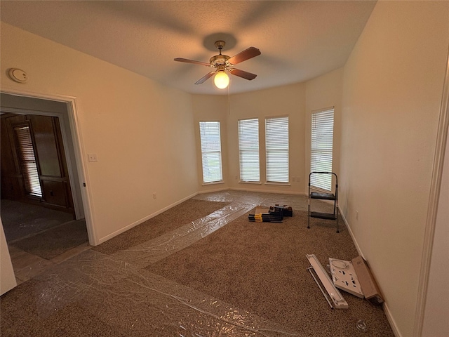 carpeted empty room with baseboards, a textured ceiling, and a ceiling fan