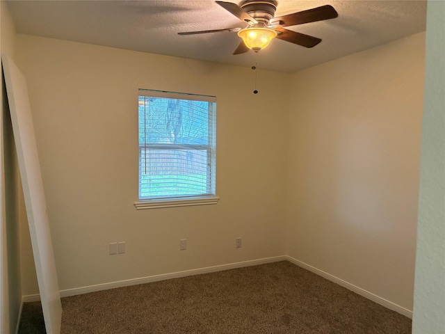 empty room featuring a textured ceiling, baseboards, dark carpet, and ceiling fan