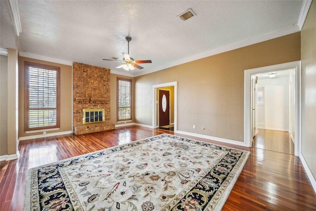 living area with a wealth of natural light, visible vents, a brick fireplace, and crown molding