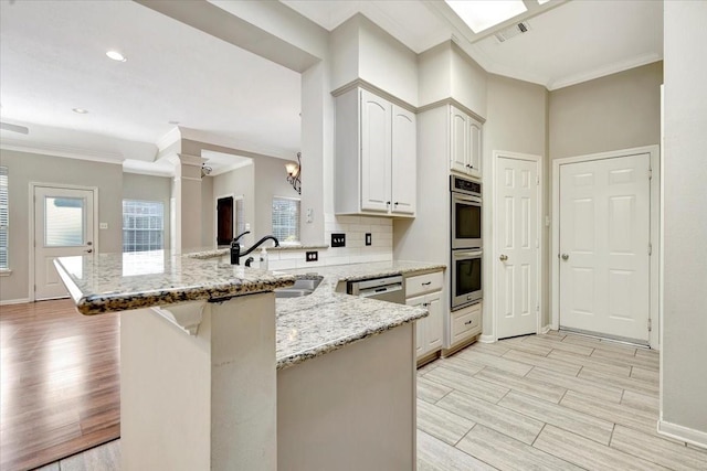 kitchen featuring light stone counters, visible vents, wood tiled floor, a sink, and a peninsula