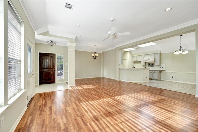 unfurnished living room featuring light wood finished floors, visible vents, ornamental molding, baseboards, and ceiling fan with notable chandelier