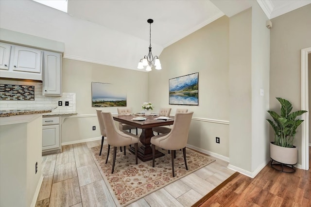 dining room with light wood-style floors, baseboards, a chandelier, and crown molding