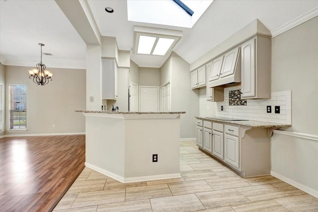 kitchen with a peninsula, light stone counters, decorative backsplash, and wood finish floors