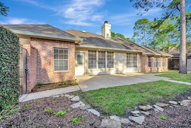 rear view of property with a patio, a chimney, fence, a yard, and brick siding