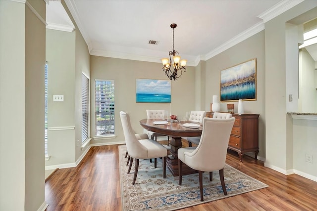 dining room with crown molding, visible vents, a notable chandelier, and wood finished floors