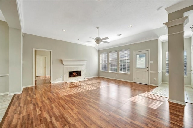 unfurnished living room with light wood-style floors, decorative columns, a fireplace, and visible vents