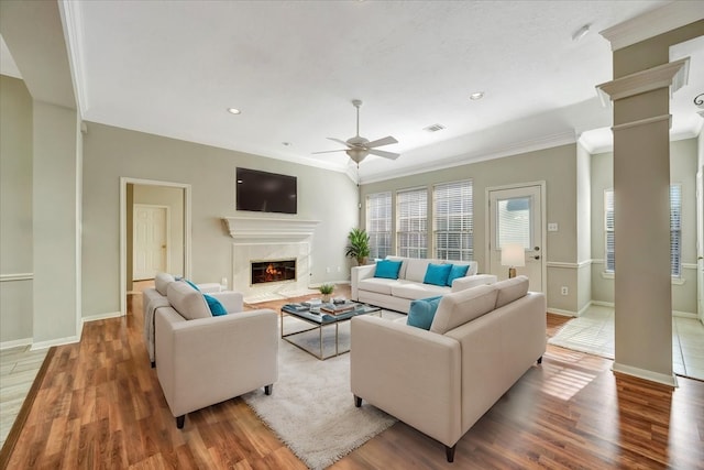 living area featuring decorative columns, visible vents, a high end fireplace, wood finished floors, and baseboards