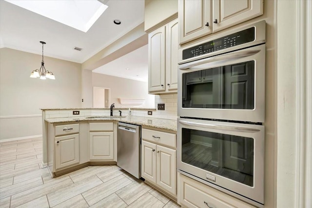 kitchen featuring stainless steel appliances, a peninsula, a sink, decorative backsplash, and pendant lighting