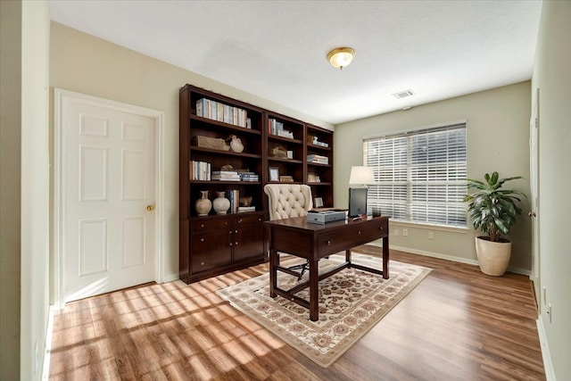 home office featuring light wood-style floors, visible vents, and baseboards