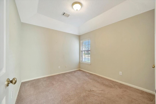 spare room featuring a textured ceiling, carpet flooring, visible vents, baseboards, and a tray ceiling