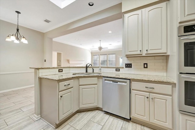 kitchen featuring tasteful backsplash, visible vents, appliances with stainless steel finishes, a sink, and a peninsula