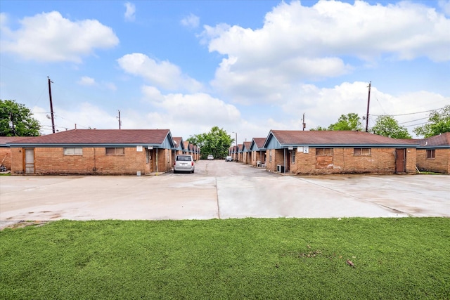 exterior space featuring concrete driveway, brick siding, and a lawn