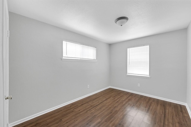 unfurnished room with dark wood-style floors, baseboards, and a textured ceiling