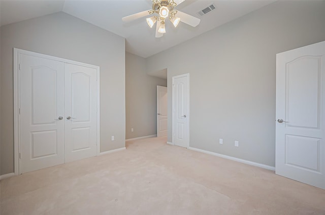 unfurnished bedroom featuring light colored carpet, visible vents, baseboards, vaulted ceiling, and a closet