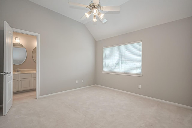 unfurnished bedroom with lofted ceiling, ensuite bathroom, light carpet, a sink, and baseboards