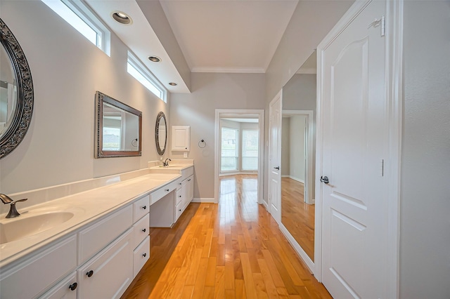 bathroom with double vanity, crown molding, a sink, and wood finished floors