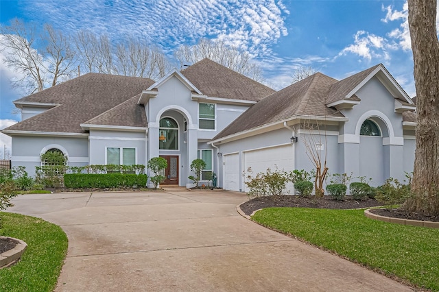 view of front facade featuring a garage, driveway, a shingled roof, and stucco siding