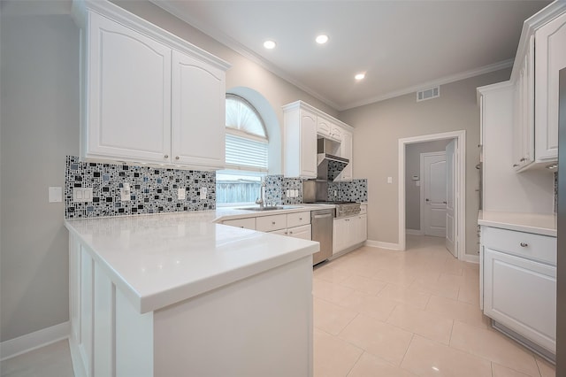 kitchen with a peninsula, stainless steel appliances, white cabinetry, visible vents, and ornamental molding