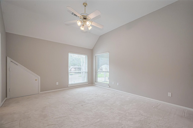 carpeted empty room with vaulted ceiling, visible vents, a ceiling fan, and baseboards