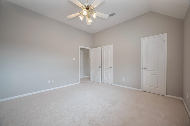 unfurnished bedroom with visible vents, light carpet, vaulted ceiling, ceiling fan, and baseboards