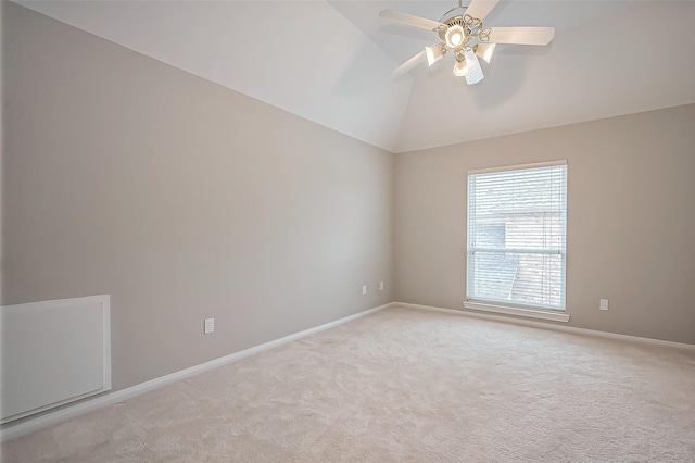 spare room with light carpet, ceiling fan, vaulted ceiling, and baseboards