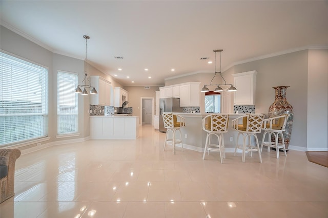 kitchen with a peninsula, white cabinetry, ornamental molding, and a kitchen breakfast bar