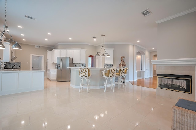 kitchen featuring arched walkways, visible vents, white cabinetry, a peninsula, and stainless steel fridge with ice dispenser