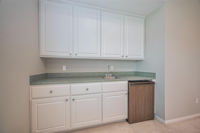 kitchen featuring light countertops, white cabinets, a sink, and baseboards