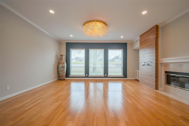 unfurnished living room featuring light wood finished floors, ornamental molding, a fireplace, and baseboards