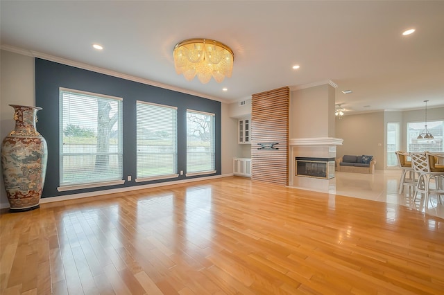 unfurnished living room with ornamental molding, light wood-type flooring, and a multi sided fireplace