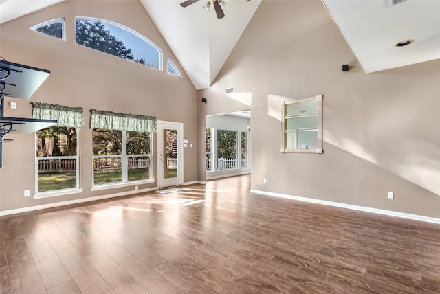 unfurnished living room with visible vents, ceiling fan, wood finished floors, high vaulted ceiling, and baseboards