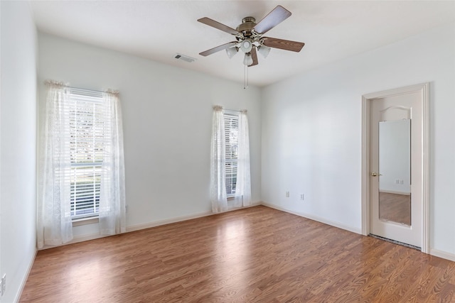 empty room featuring visible vents, ceiling fan, baseboards, and wood finished floors