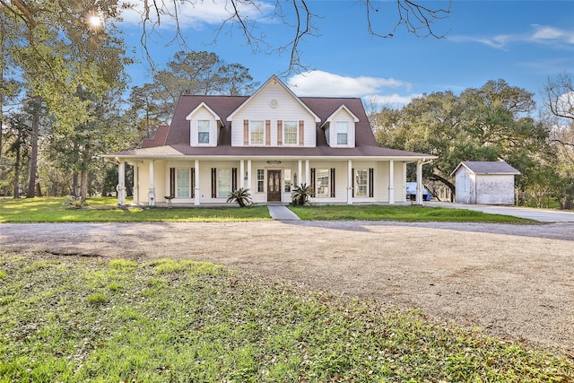 country-style home featuring driveway, a storage shed, covered porch, an outdoor structure, and a front lawn