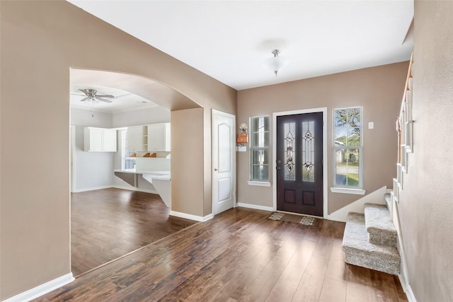 entrance foyer featuring dark wood-style floors, baseboards, and arched walkways