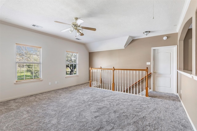 unfurnished room with a textured ceiling, visible vents, crown molding, and carpet flooring