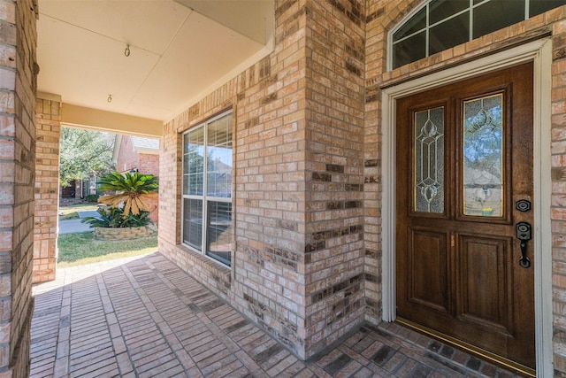 view of exterior entry with covered porch and brick siding