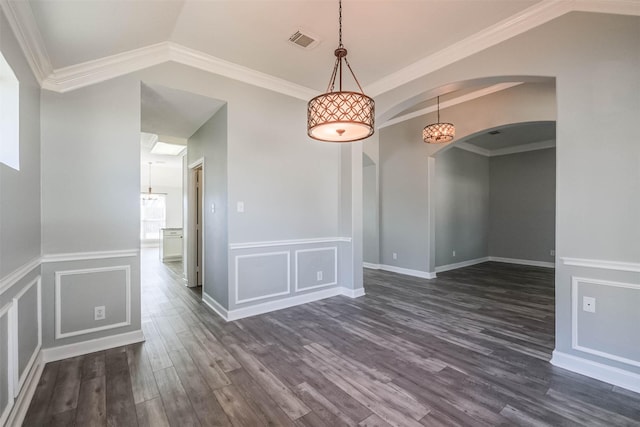 empty room with visible vents, arched walkways, dark wood finished floors, ornamental molding, and a decorative wall