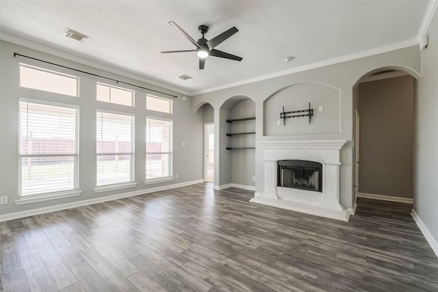 unfurnished living room featuring a fireplace with raised hearth, built in shelves, dark wood finished floors, and visible vents