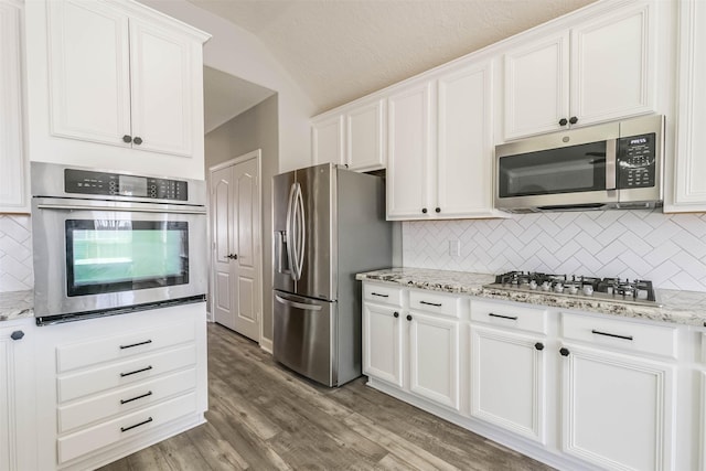 kitchen featuring decorative backsplash, light wood-style flooring, appliances with stainless steel finishes, light stone countertops, and white cabinetry