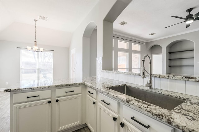 kitchen with a healthy amount of sunlight, a sink, visible vents, and light stone countertops