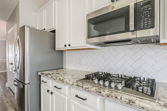 kitchen with appliances with stainless steel finishes, white cabinets, and backsplash