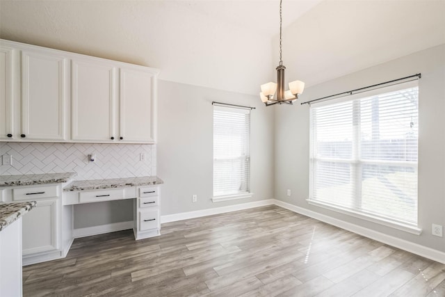 kitchen featuring a healthy amount of sunlight, light stone countertops, white cabinets, and backsplash