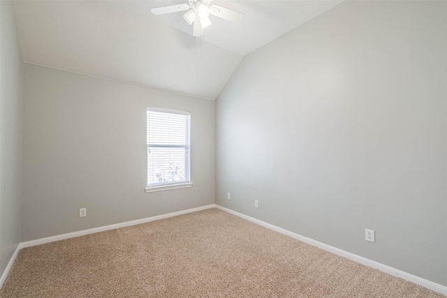 spare room featuring lofted ceiling, carpet flooring, a ceiling fan, and baseboards