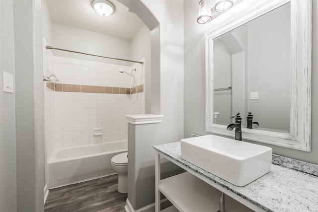 full bath featuring  shower combination, vanity, toilet, and wood finished floors